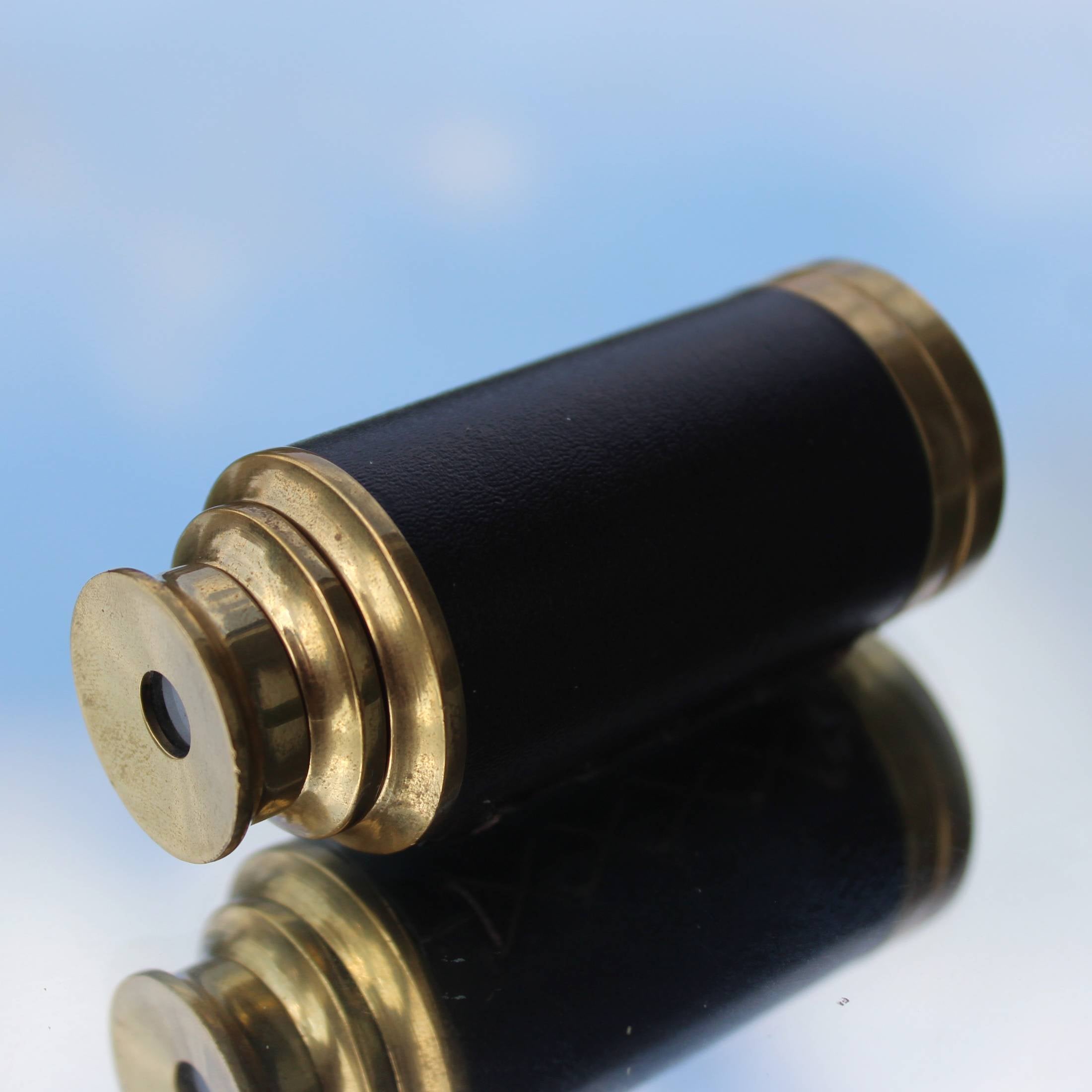 Magis Art Shop vintage-style brass monocular telescope with a black leather grip, shown in its collapsed position.