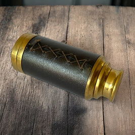 Magis Art Shop vintage-style brass monocular telescope with a dark brown stitched leather grip on a wooden surface