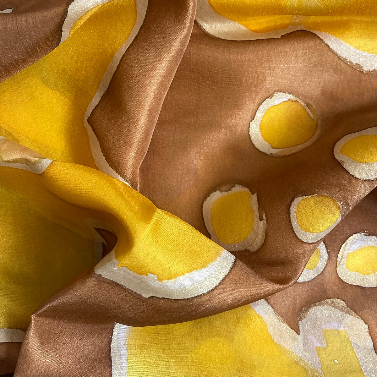 Magis Art Shop hand-painted silk scarf in brown and yellow with abstract circular patterns and a lustrous finish.