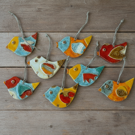 Magis Art Shop ceramic bird ornaments with colorful glazed patterns and hanging strings on a rustic wooden background