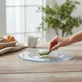 Magis Art Shop clear glass serving plate for desserts on a rustic wooden table with a sprig of rosemary