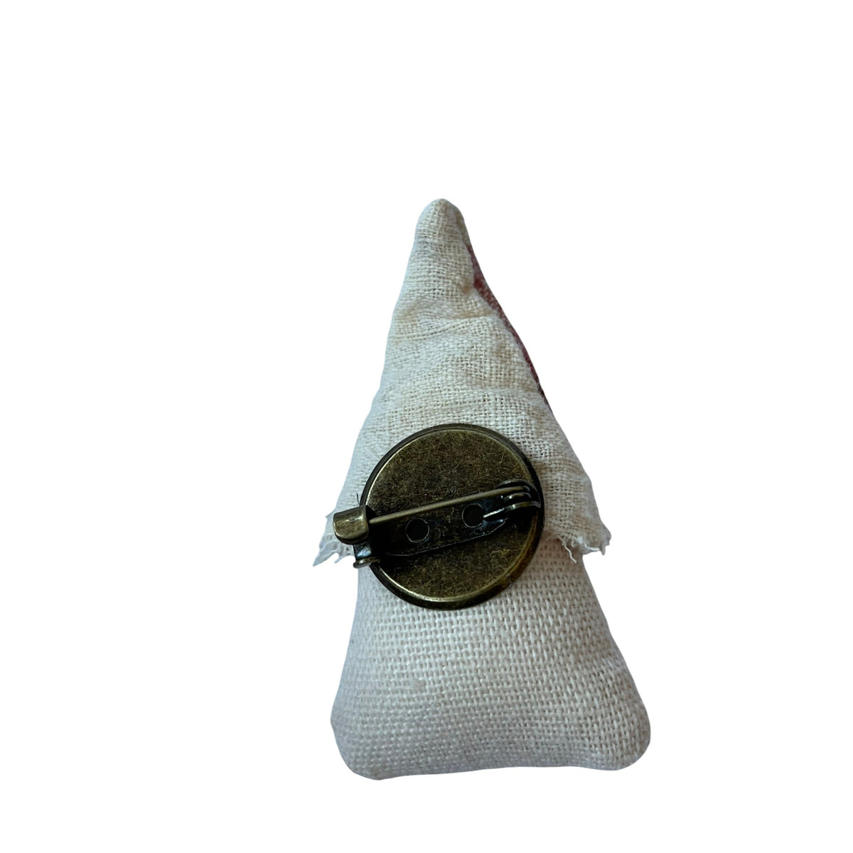 Back view of a Magis Art Shop fabric house brooch showing the bronze metal pin mechanism on a cream textile base.
