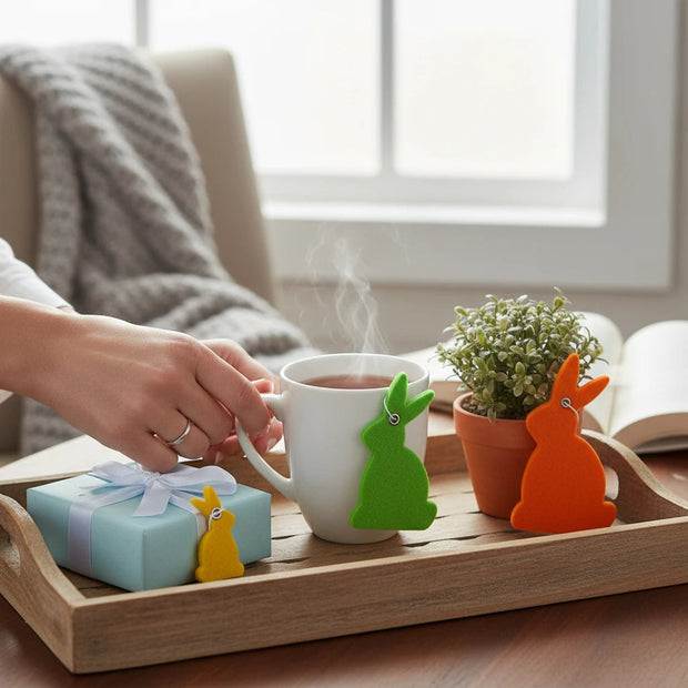 Magis Art Shop felt bunny hanging decorations in yellow, green, and orange on a wooden tray with a tea cup.