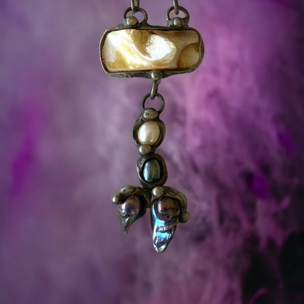 Magis Art Shop artisan necklace featuring fluorite, mother of pearl, and river pearls in a handcrafted tin setting.