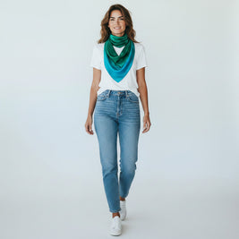Magis Art Shop green and blue silk scarf worn by a woman in a white t-shirt and jeans against a white background.