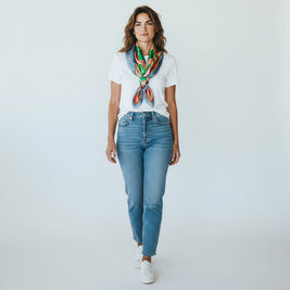 Magis Art Shop silk scarf in green and orange worn by a woman in a white t-shirt and blue jeans