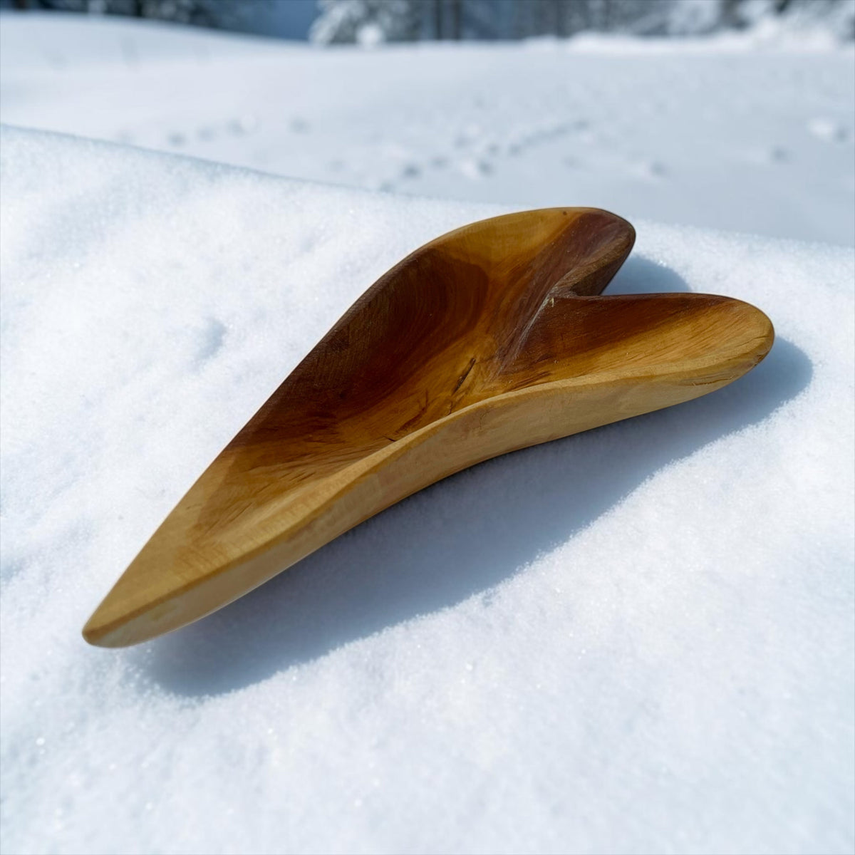 Magis Art Shop hand-carved wooden heart-shaped bowl for snacks, resting on a snowy outdoor surface.