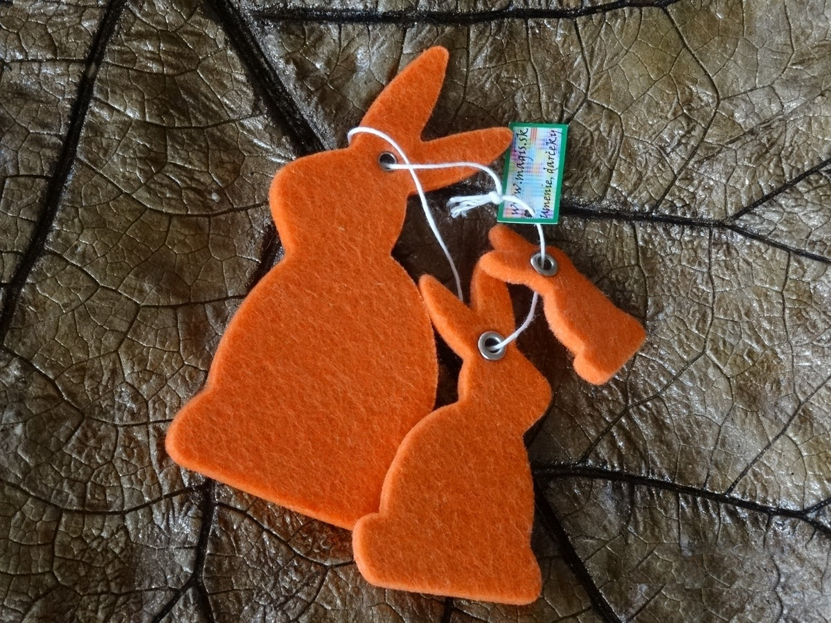 Magis Art Shop orange felt bunny hanging decorations in two different sizes on a dark leaf background