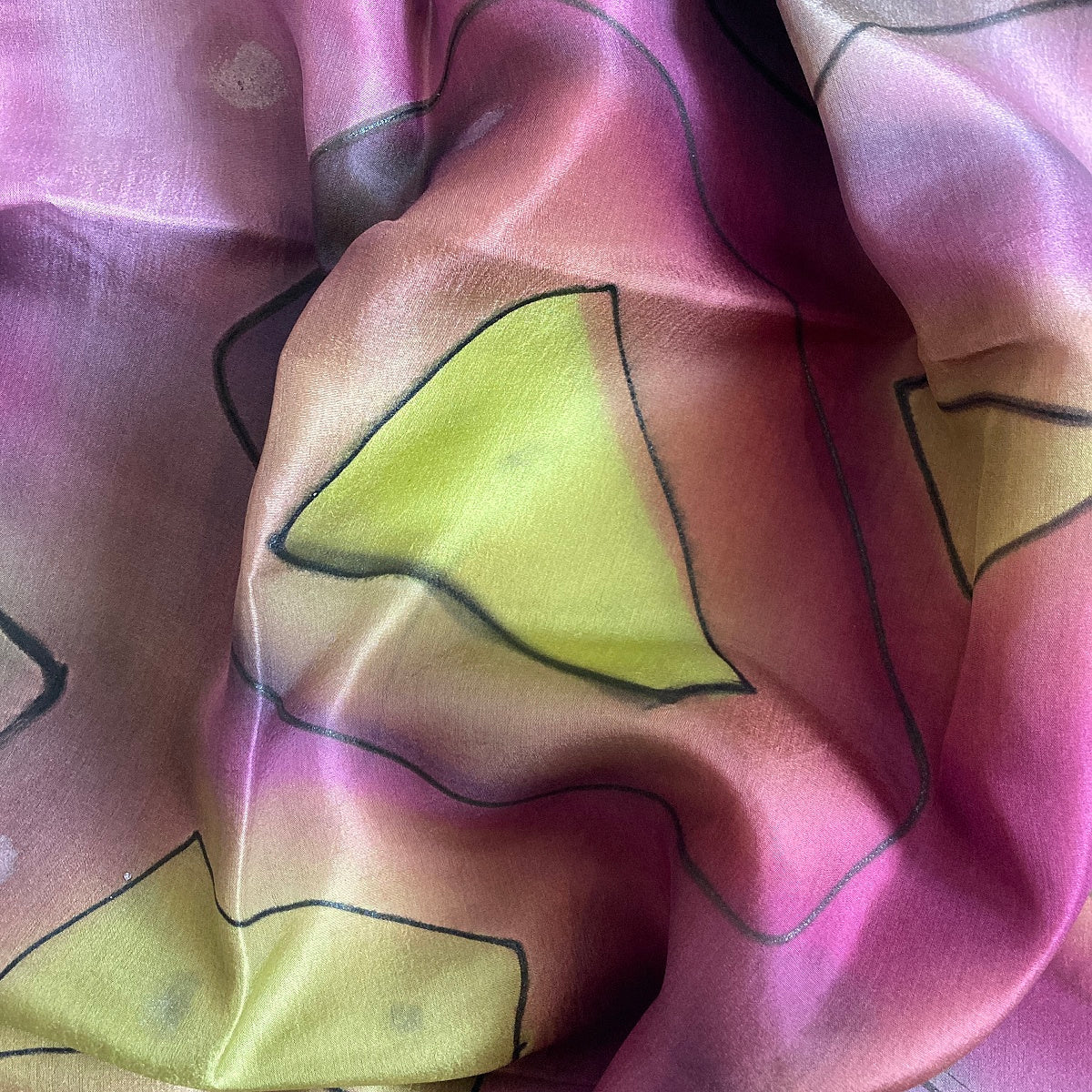 Magis Art Shop hand-painted silk scarf with purple and green abstract geometric patterns and soft fabric texture.