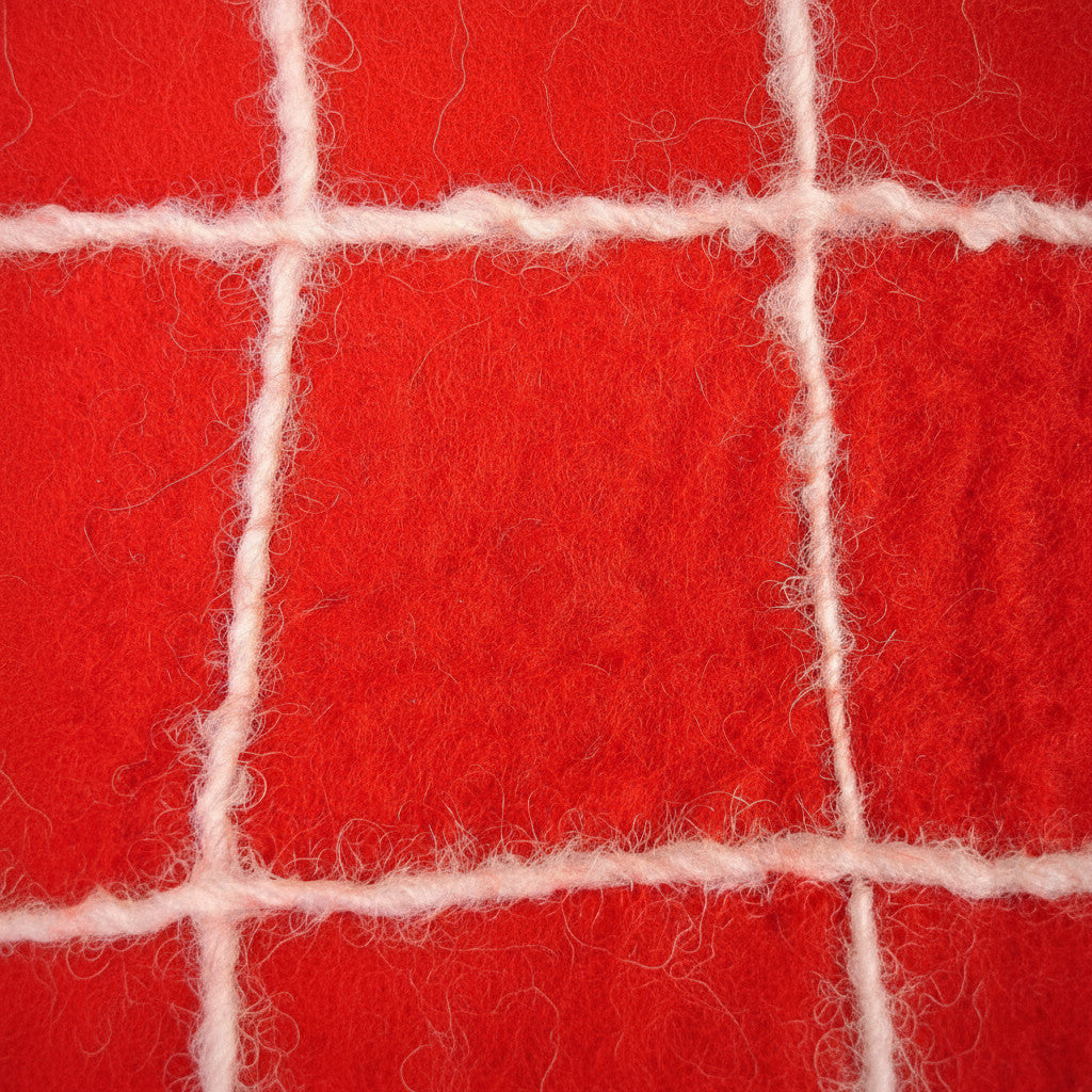 Close-up of a red felt bag by Magis Art Shop featuring a textured grid pattern with white wool stitching.