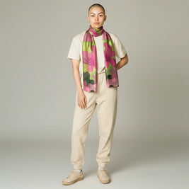 Model wearing a hand-painted green and pink 100% silk scarf by Ria Berec, available at Magis Art Shop.