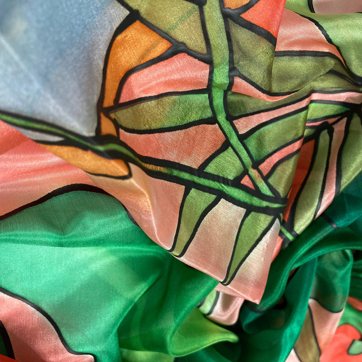 Magis Art Shop silk scarf featuring abstract green and orange hand-painted patterns with bold black outlines.