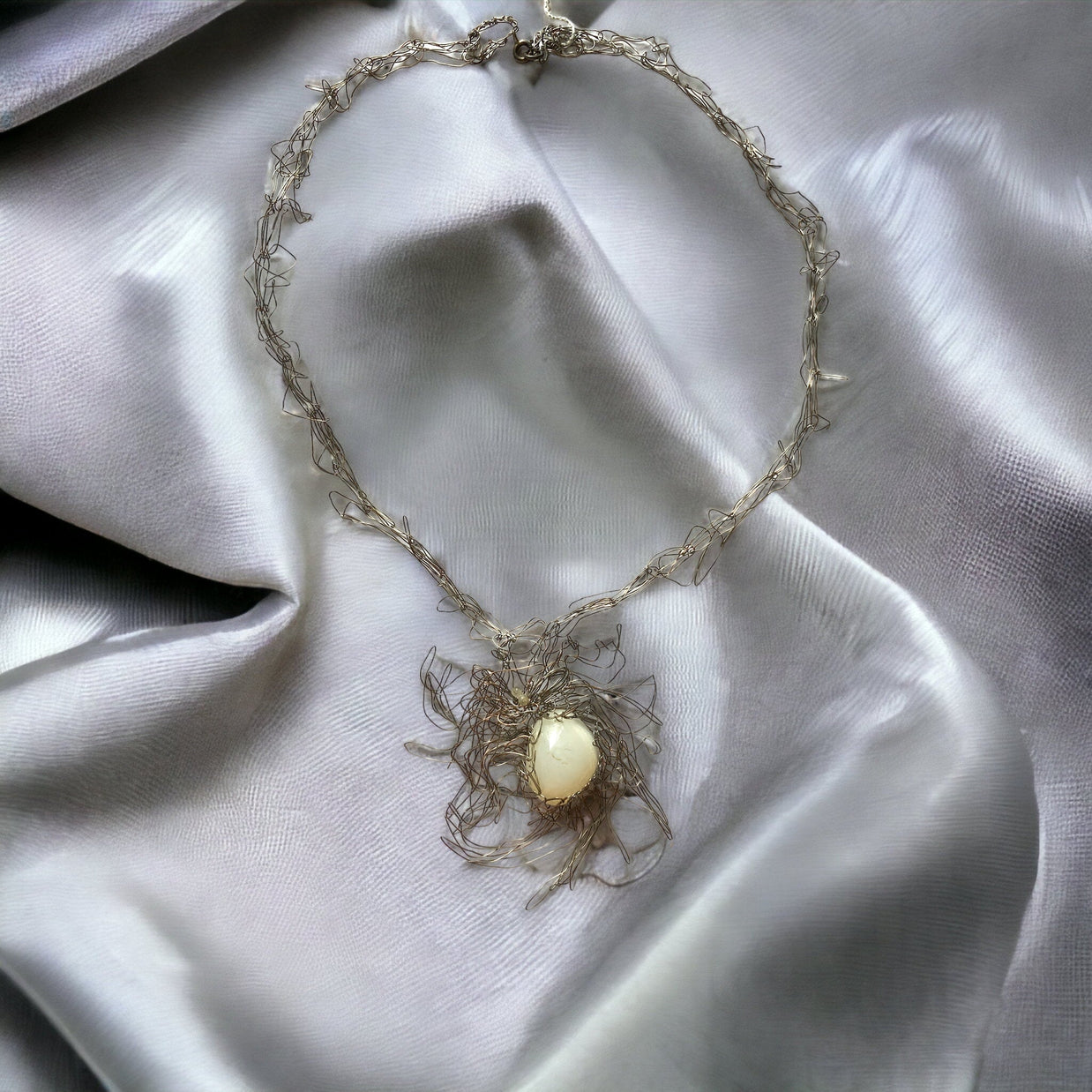 Magis Art Shop silver wire necklace featuring a delicate woven metal design and a central white stone pendant