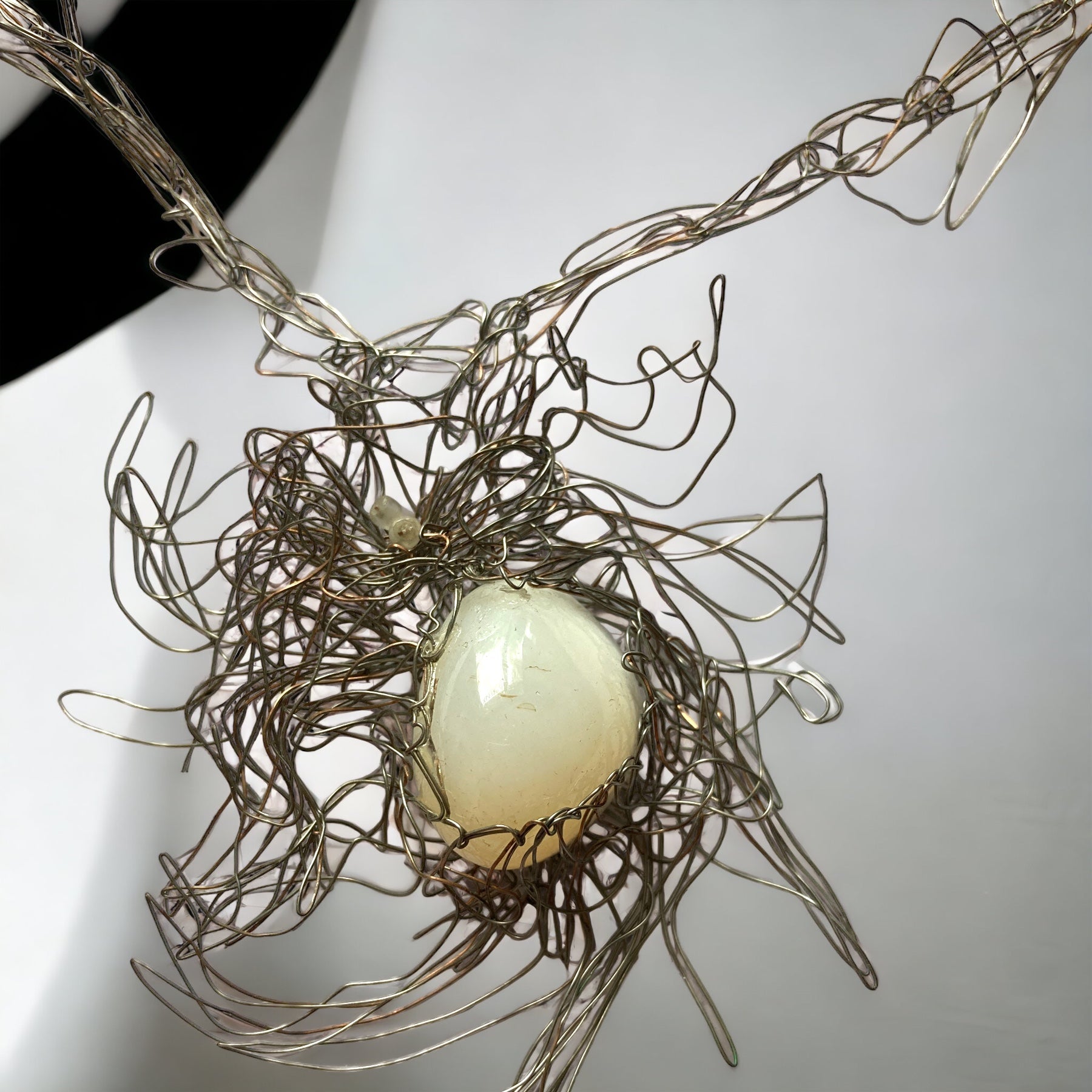 Magis Art Shop silver wire necklace featuring an organic white stone set in an intricate, tangled metal design.