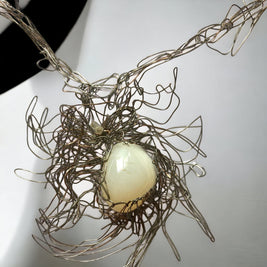 Magis Art Shop silver wire necklace featuring an organic white stone set in an intricate, tangled metal design.