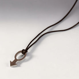 Magis Art Shop stainless steel pendant necklace featuring a minimalist arrow design on a dark brown cord