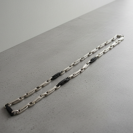 Magis Art Shop stainless steel chain necklace with modern black accent links on a grey surface