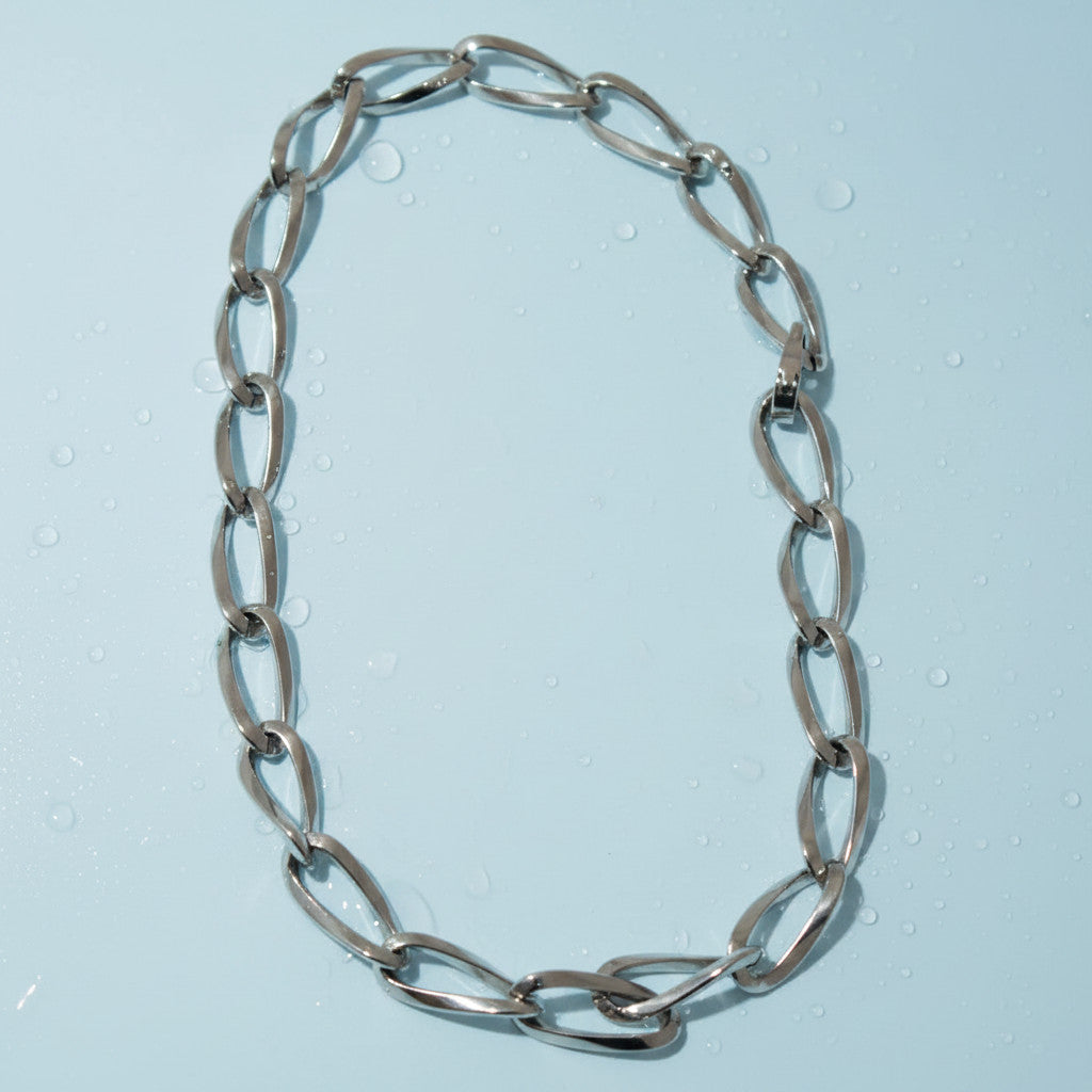 Magis Art Shop stainless steel chain necklace with large oval links and a secure clasp on a light blue background.