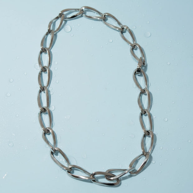 Magis Art Shop stainless steel chain necklace with large oval links and a secure clasp on a light blue background.