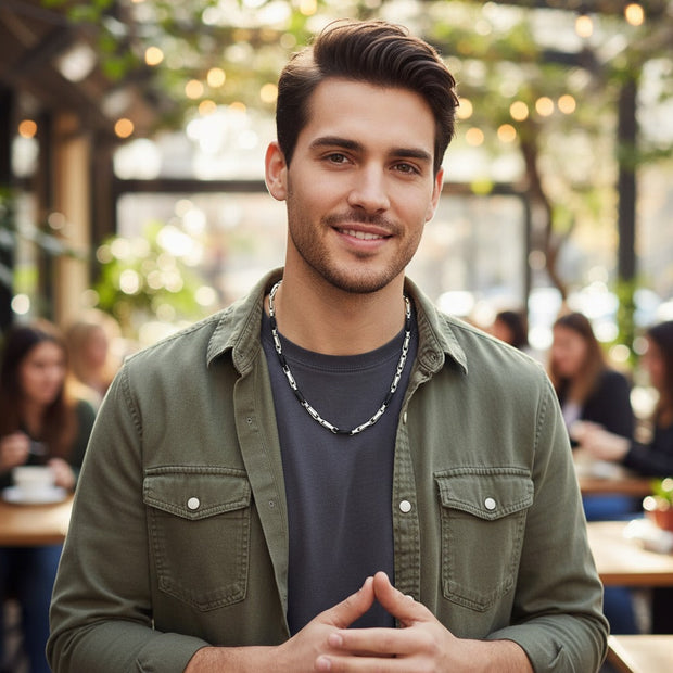 Magis Art Shop stainless steel necklace with black accents worn by a smiling man in a casual olive green shirt