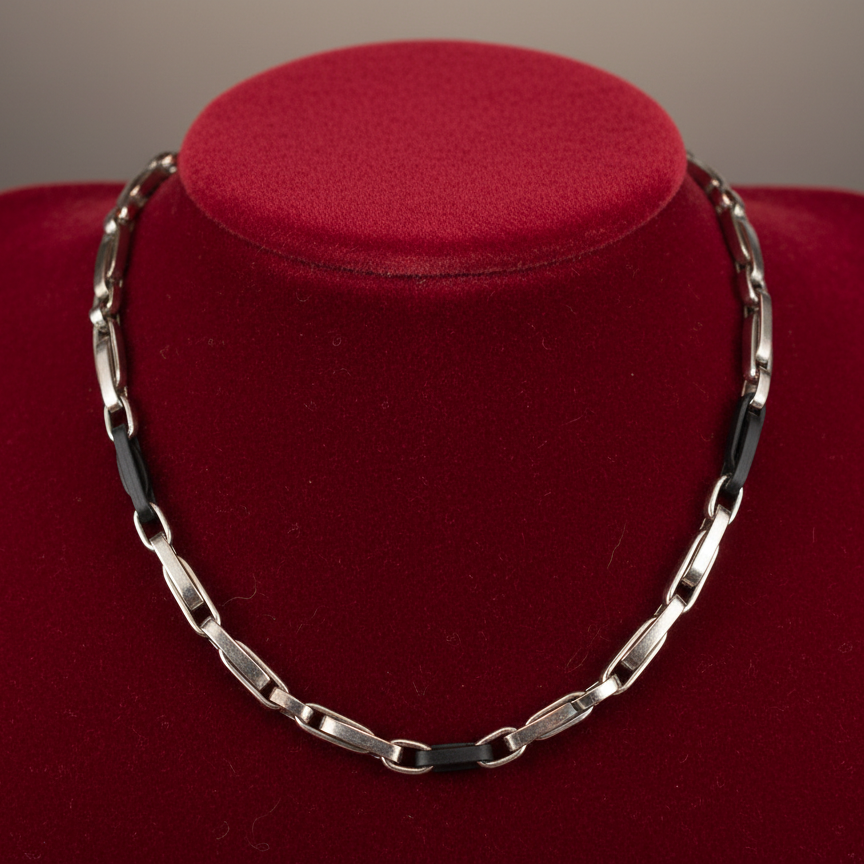 Magis Art Shop stainless steel chain necklace with black accents displayed on a red velvet bust