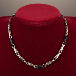 Magis Art Shop stainless steel chain necklace with black accents displayed on a red velvet bust