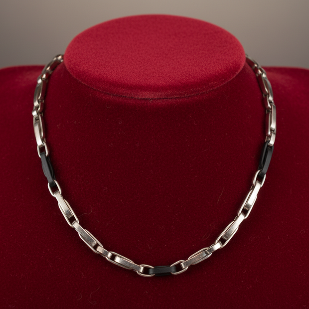 Magis Art Shop stainless steel chain necklace with black accents displayed on a red velvet bust
