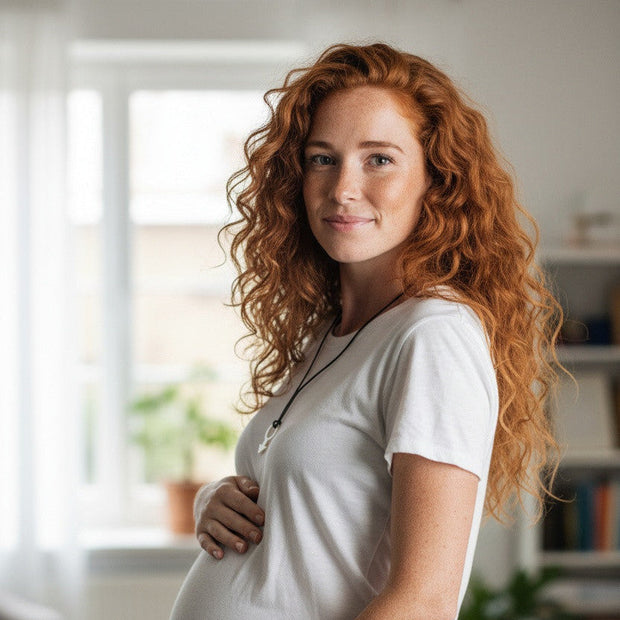 Magis Art Shop stainless steel pendant necklace worn by a pregnant woman with long red hair in a bright room