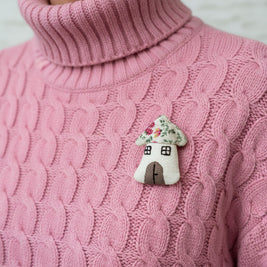 Magis Art Shop handmade textile house brooch with a floral roof pinned on a pink cable-knit turtleneck sweater