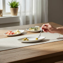 Magis Art Shop white ceramic boat-shaped serving bowl holding olives on a wooden dining table