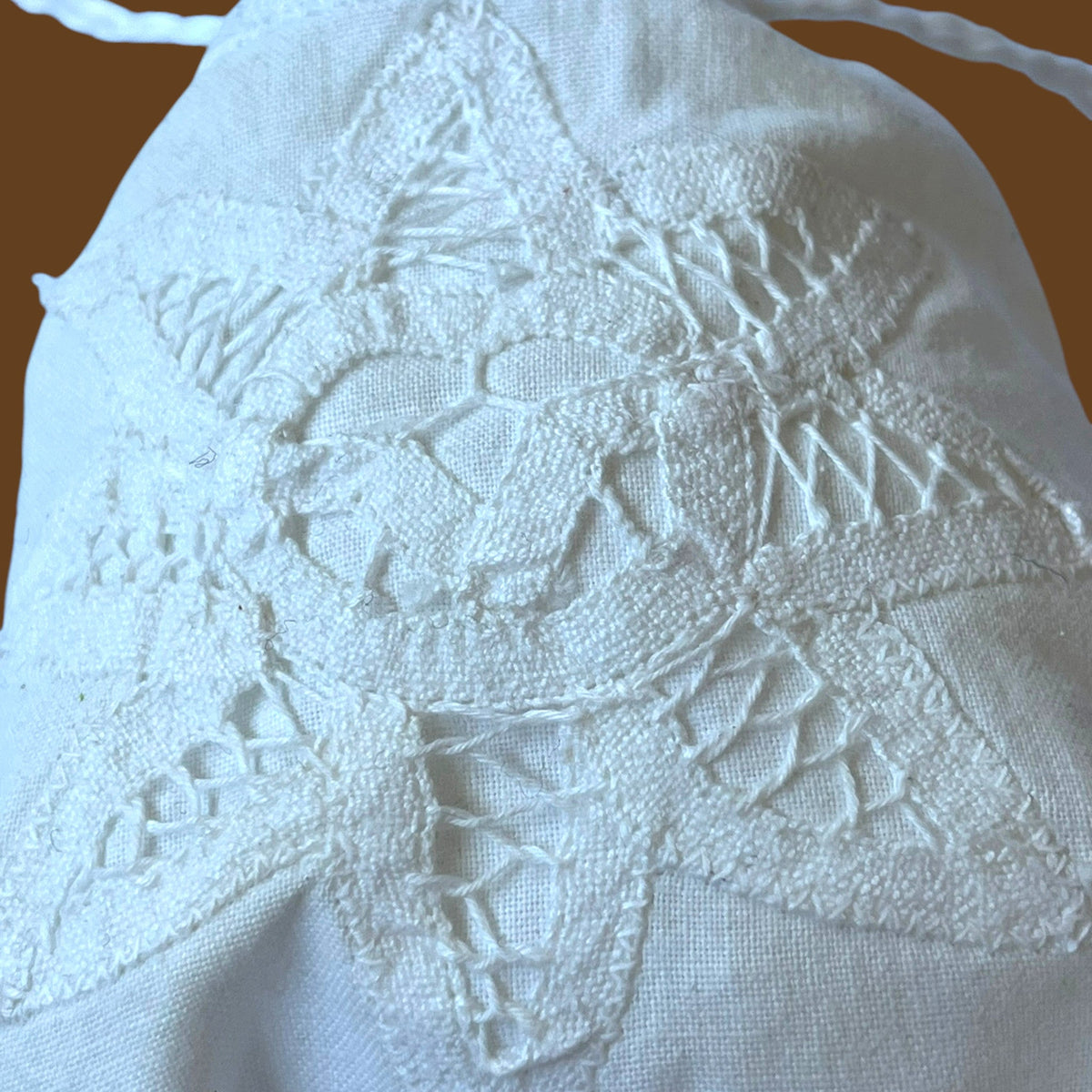 Magis Art Shop white cotton drawstring pouch featuring intricate white star-shaped embroidery and lace detailing.