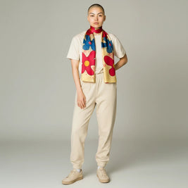 Model wearing a yellow Ria Berec hand-painted silk scarf with blue and red floral patterns from Magis Art Shop